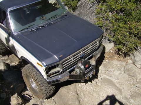 1986 Ford Bronco - This two-tone 1986 Ford Bronco navigates a rocky trail, equipped with a front-mounted winch.