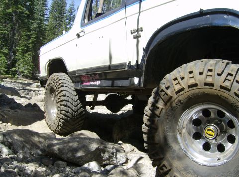 1986 Ford Bronco - This vehicle is navigating a challenging rocky trail in a wooded area.