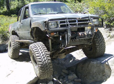 1986 Ford Bronco - This modified truck navigates a rocky trail with its front end angled towards the camera.