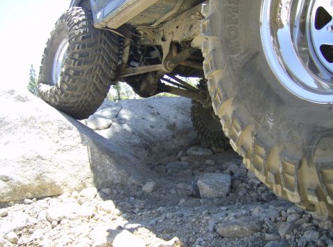 1986 Ford Bronco - Vehicle navigating challenging rocky terrain, showing suspension and large tires.