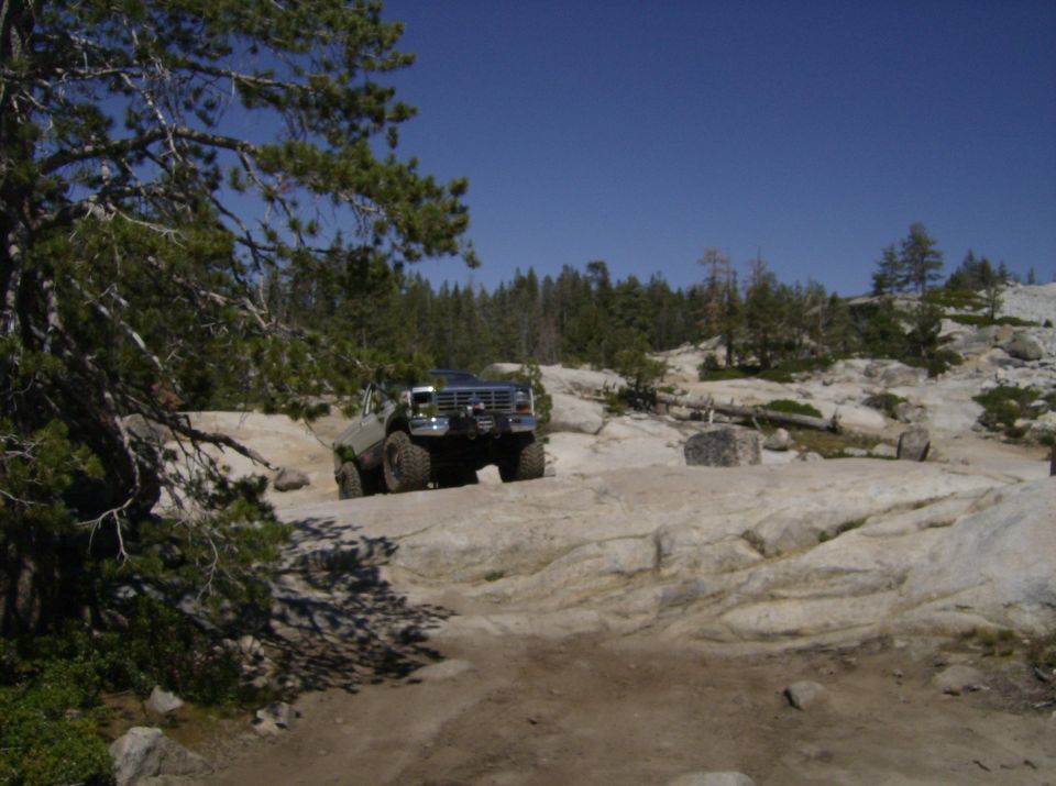 Green off-road SUV navigating rocky terrain, front view