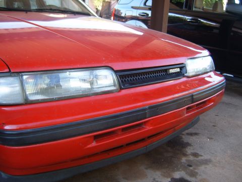 2001 Pontiac Trans Am - Front view of a red Mazda, showing the grille and headlight detail.
