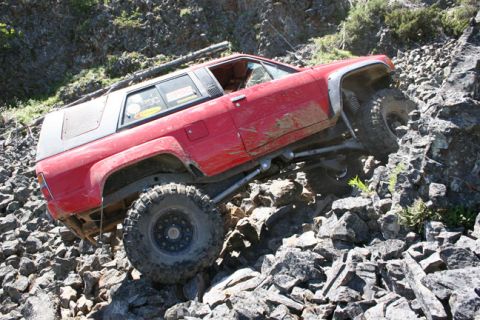 1993 Ford Bronco - A red SUV navigates a challenging rocky terrain, demonstrating its off-road capabilities.