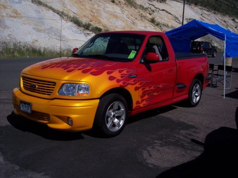 1972 Ford Ranchero - A red pickup truck with a yellow front and flame graphics is parked outdoors.