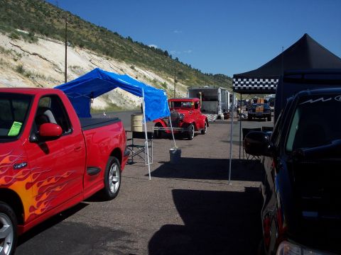 1972 Ford Ranchero - A red vintage car is parked under a blue canopy at an outdoor event.