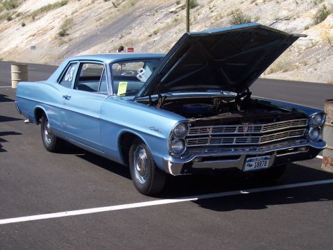 1972 Ford Ranchero - A light blue 1967 Ford Galaxie 500 is shown with its hood up, parked on a paved surface with a hillside in the background.