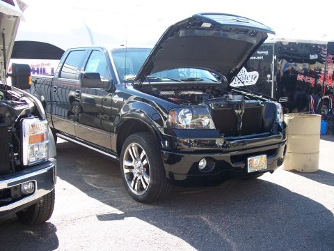 1972 Ford Ranchero - A black pickup truck is parked with its hood open, alongside another vehicle.
