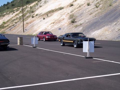 1972 Ford Ranchero - Two classic Ford Mustangs are lined up on an asphalt surface with a barren hillside in the background.