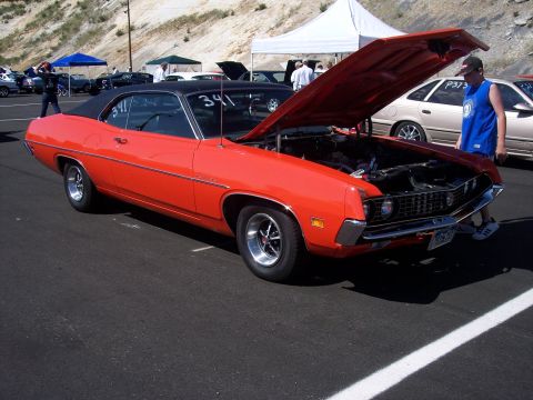 1972 Ford Ranchero - An orange 1970 Ford Ranchero with its hood open is parked at an outdoor event.