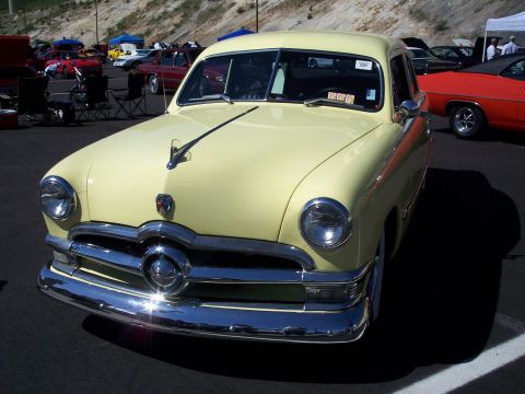 1972 Ford Ranchero - A pale yellow coupe from the 1950s is parked at an outdoor car show.