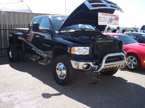 1972 Ford Ranchero - A black 2004 Dodge Ram 3500 dually pickup truck is displayed with its hood open, revealing engine details and a sign.