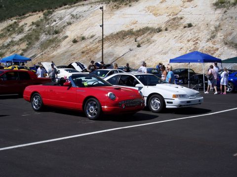 1972 Ford Ranchero - A gathering of cars and people at an outdoor event, with a red convertible and a white coupe in the foreground.