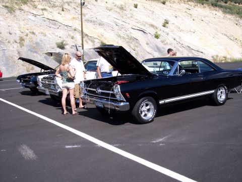1972 Ford Ranchero - A black coupe with white racing stripes is displayed with its hood open at an outdoor car show.