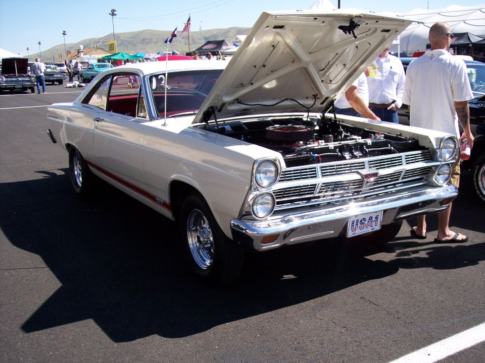 White 1967 Ford Fairlane coupe with red stripe, hood open, chrome grille, and USA1 license plate