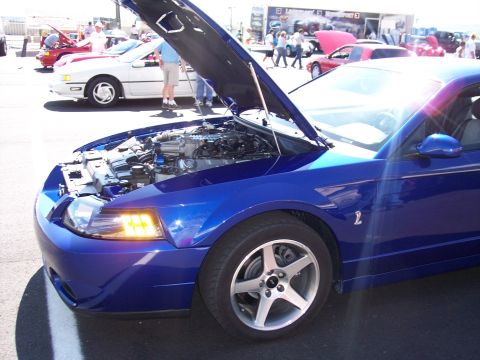 1972 Ford Ranchero - A blue Ford Mustang is displayed with its hood open, revealing the engine, at an outdoor car show.