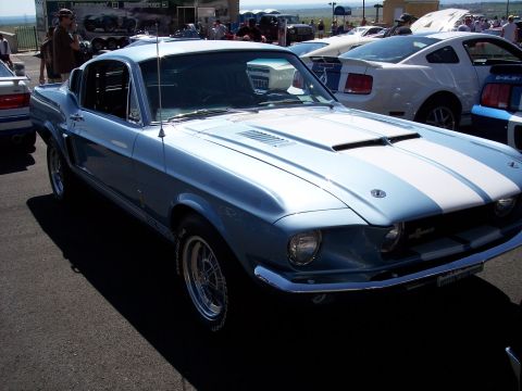 1972 Ford Ranchero - A classic light blue Mustang with white racing stripes is displayed at an outdoor event with other vehicles.