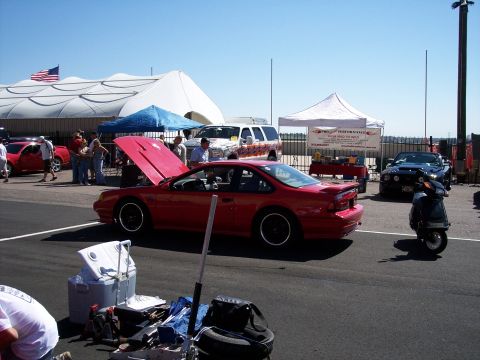 1972 Ford Ranchero - A red coupe with its hood open sits on display at an outdoor event, with other vehicles and tents in the background.