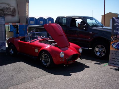 1972 Ford Ranchero - A classic red convertible is displayed next to a modern pickup truck at an outdoor event.