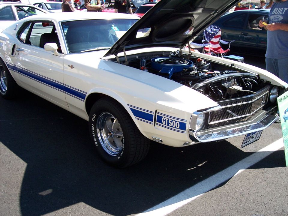 White 1969 Ford Mustang GT500 with blue stripes, hood open showing engine