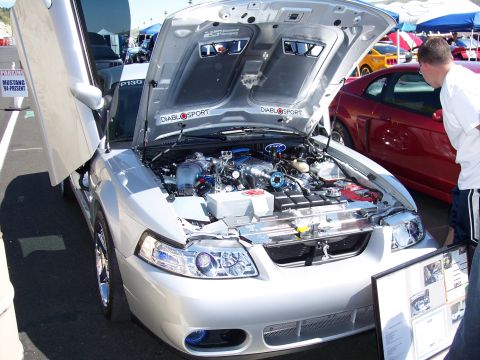 1972 Ford Ranchero - A silver car with its hood and doors open is displayed at an outdoor event, with a person looking at the engine.