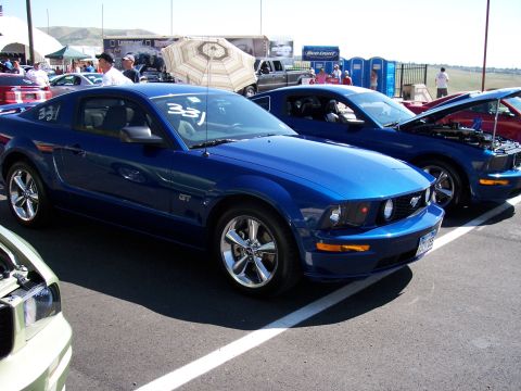 1972 Ford Ranchero - Two blue Ford Mustangs are parked side-by-side at an outdoor event, with one having its hood open.