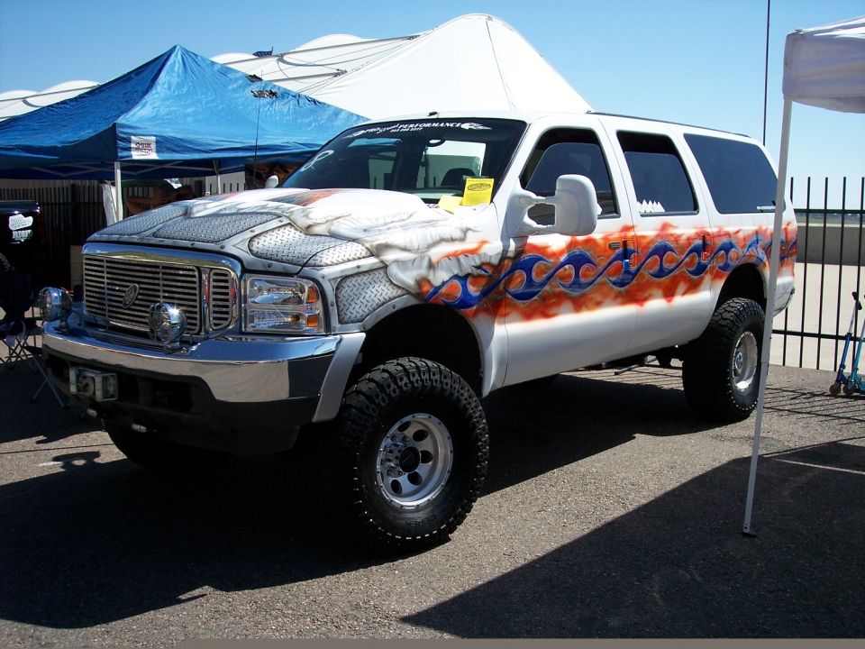 White Ford Excursion SUV with custom flame graphics and diamond plate hood wrap