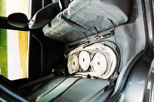 Rear bench seat lifted to show coiled tow straps stored beneath in SUV interior