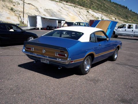 1972 Ford Ranchero - A blue 1970 Ford Maverick Grabber is parked with its hood open, showing off its engine bay.