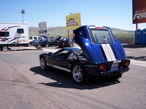 1972 Ford Ranchero - A blue sports car with white racing stripes is parked at a race track, with its engine compartment open.