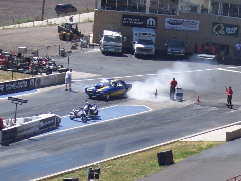 1972 Ford Ranchero - A drag car performs a burnout on the track, creating a cloud of smoke, with a motorcycle waiting.
