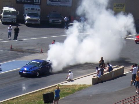 1972 Ford Ranchero - A blue car performs a burnout on the drag strip, generating a large cloud of smoke.