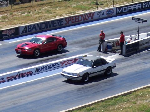 1972 Ford Ranchero - Two cars compete on the drag strip at Bandimere Speedway, with spectators watching from the side.