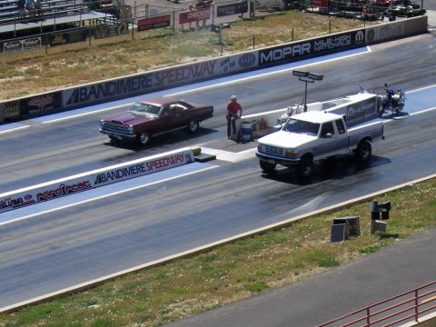 1972 Ford Ranchero - A drag race is underway at Bandimere Speedway, with a classic coupe and a modern pickup truck competing.