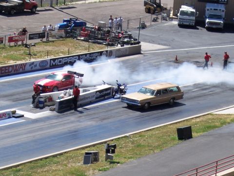 1972 Ford Ranchero - A gold station wagon and a red muscle car are on a drag strip, with smoke billowing from the muscle car.