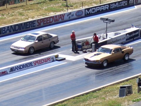 1972 Ford Ranchero - A gold 1969 Ford Mustang Mach 1 is on the drag strip, with a tan sedan in the background.