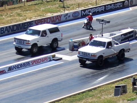 1972 Ford Ranchero - Two white Ford trucks, a pickup and a Bronco, race down Bandimere Speedway.