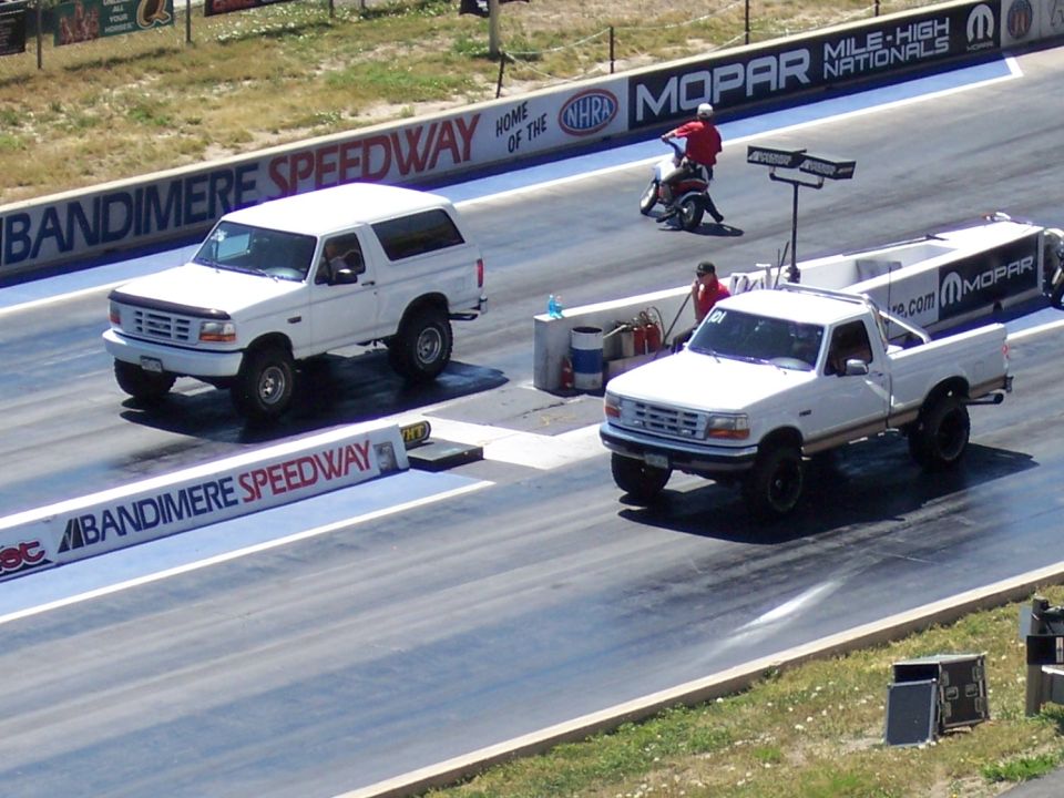 White Ford pickup truck and Bronco on drag strip
