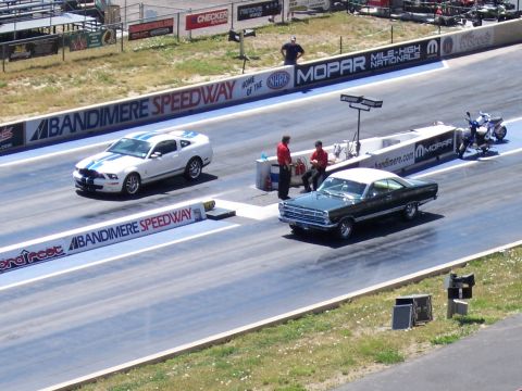 1972 Ford Ranchero - Two cars line up at the starting line of a drag strip, with a motorcycle parked nearby.