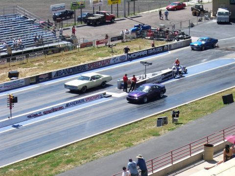 1972 Ford Ranchero - Two cars compete on the drag strip at Bandimere Speedway, with spectators in the stands.