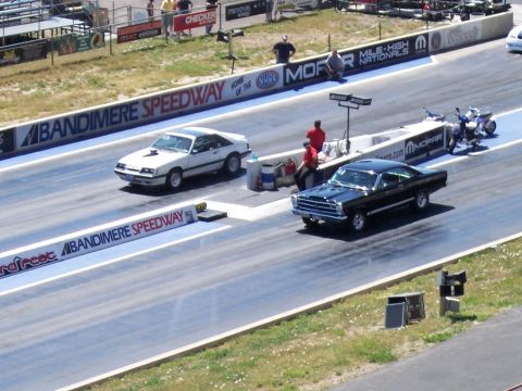 1972 Ford Ranchero - Cars compete on the drag strip at Bandimere Speedway, with spectators and signage in the background.