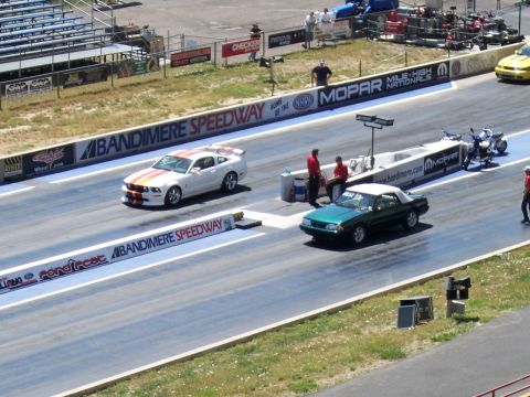 1972 Ford Ranchero - A green convertible races down the drag strip at Bandimere Speedway, with a white Mustang in the adjacent lane.