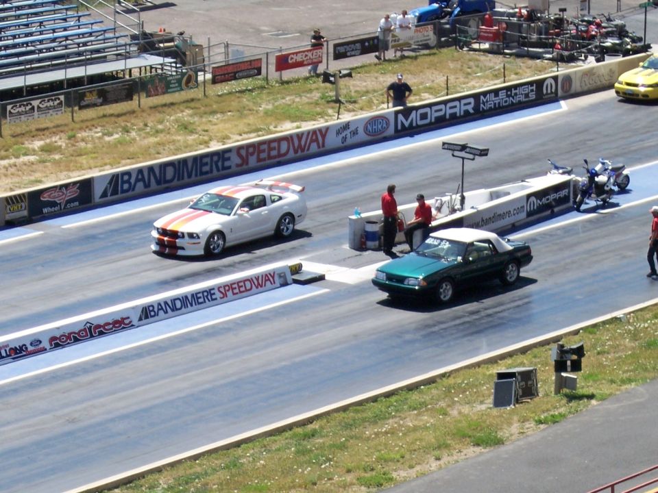 Green convertible car racing on a drag strip, side view