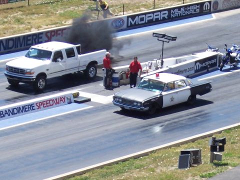 1972 Ford Ranchero - A drag race is underway at Bandimere Speedway, a modern pickup truck and a classic police cruiser.
