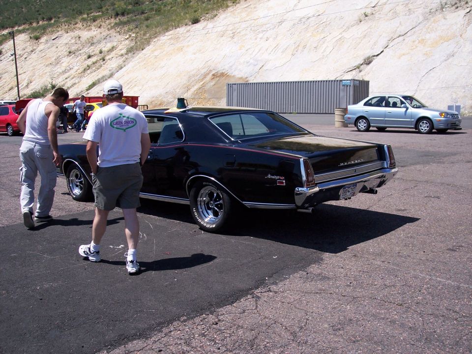 Black coupe with chrome trim and red stripe, seen from rear three-quarter angle