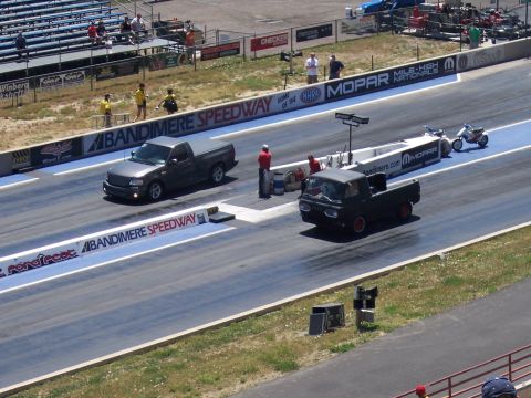 1972 Ford Ranchero - Two pickup trucks compete in a drag race at Bandimere Speedway, with spectators in the stands.