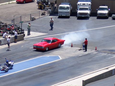 1972 Ford Ranchero - A red coupe performs a burnout on the drag strip, creating a large cloud of smoke.