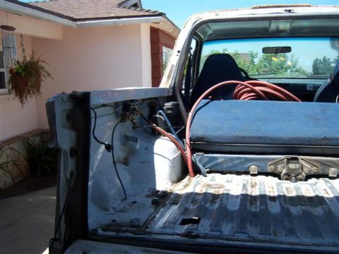 1995 Ford Bronco - The rear of a white Ford Bronco shows a blue toolbox and coiled red hose in its bed.