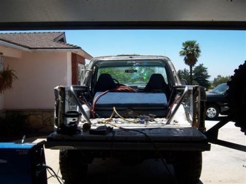 1995 Ford Bronco - Rear view of a truck bed with a custom rollcage installed. Another vehicle is parked in the background.