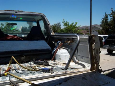 1995 Ford Bronco - Tools and equipment are laid out in the bed of a pickup truck, with a roll cage installed.