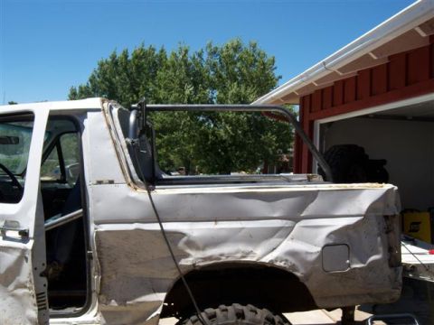 1995 Ford Bronco - This white SUV features a prominent roll cage and significant body damage, with a spare tire visible in the background.